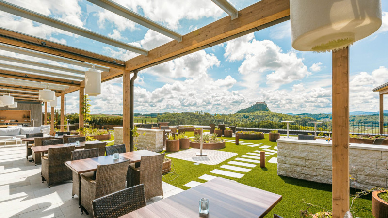 Beschattete Terrasse mit mehreren Tischen und Sitzplätzen