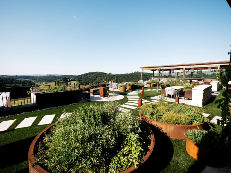 Gepflegte Terrasse mit Kräutern und grünen Pflanzen in rostfarbenen Töpfen