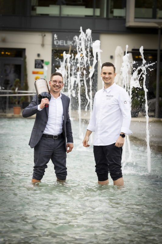 Gastgeber der Delikaterie stehen im Springbrunnen vor dem Restaurant