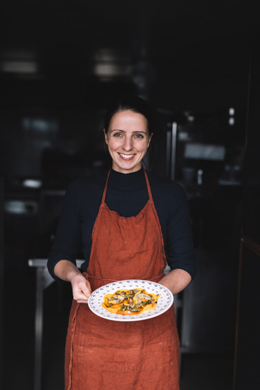 Barbara Krenn steht in der Küche und präsentiert ein Gericht am Teller (c) Slow Food Österreich Mara Hohla